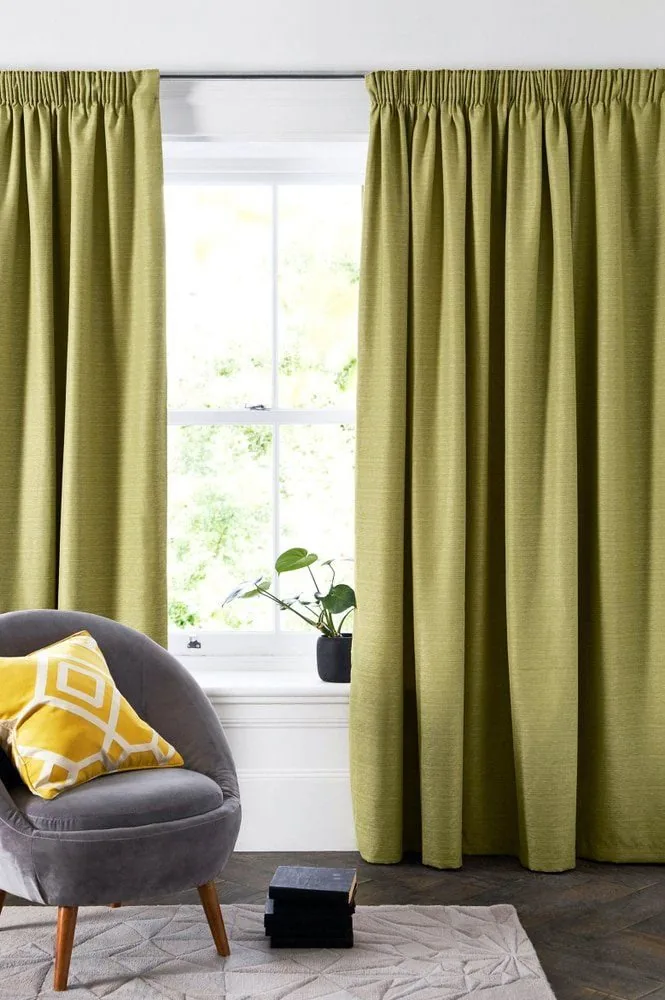 Pencil pleat curtains framing a window in a plain modern room