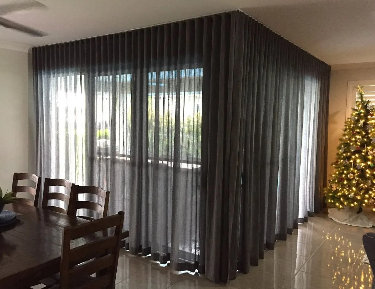 Sheer fabric hanging in fine vertical folds beside a window