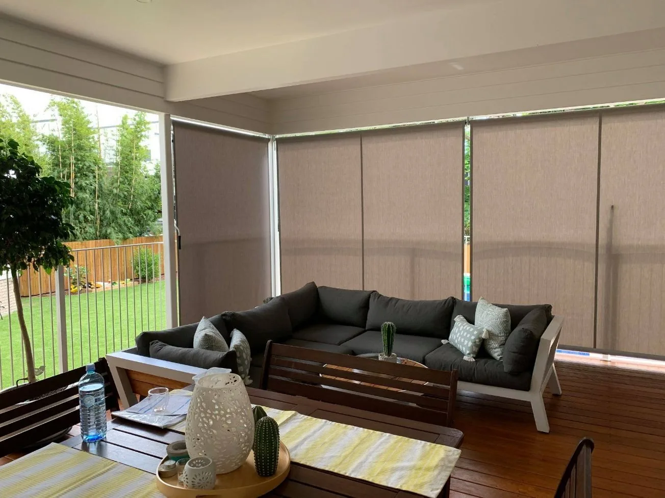 Track-guided outdoor blinds enclosing a covered patio